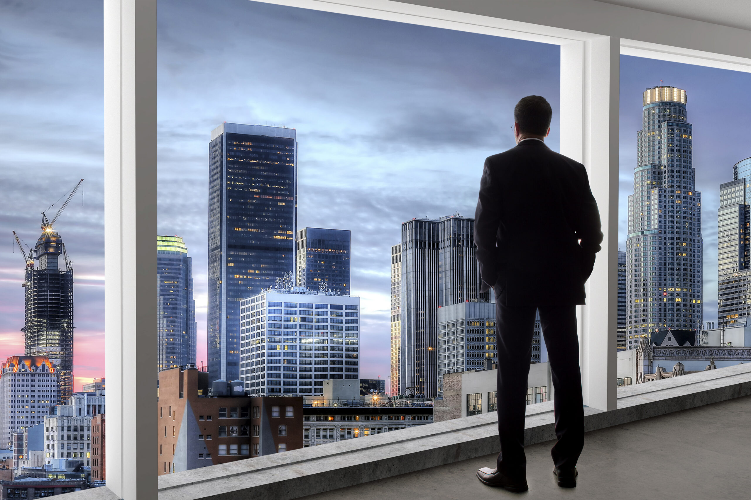 Middle aged businessman looking out a bright office window in Los Angeles and thinking